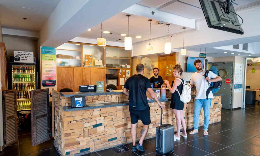 Travelers checking in at the reception desk of Abraham Tel Aviv hostel